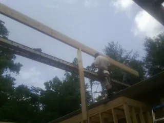 Carpenter setting a ridge beam over a new addition frame — Ice Dam Removal by Roofing Brothers in East Sparta