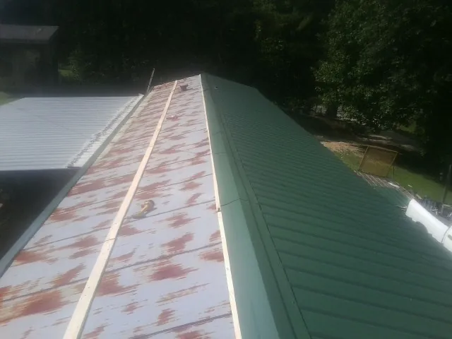 Old rusted panels beside newly installed green metal roofing — Wind Damage Roof Repair by Roofing Brothers in East Sparta