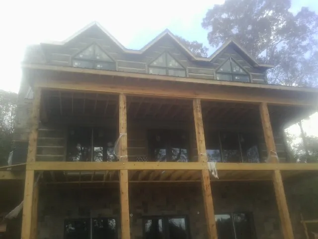 Dormers and porch framing on a large log home under construction — Roof Coating work by our crew in East Sparta