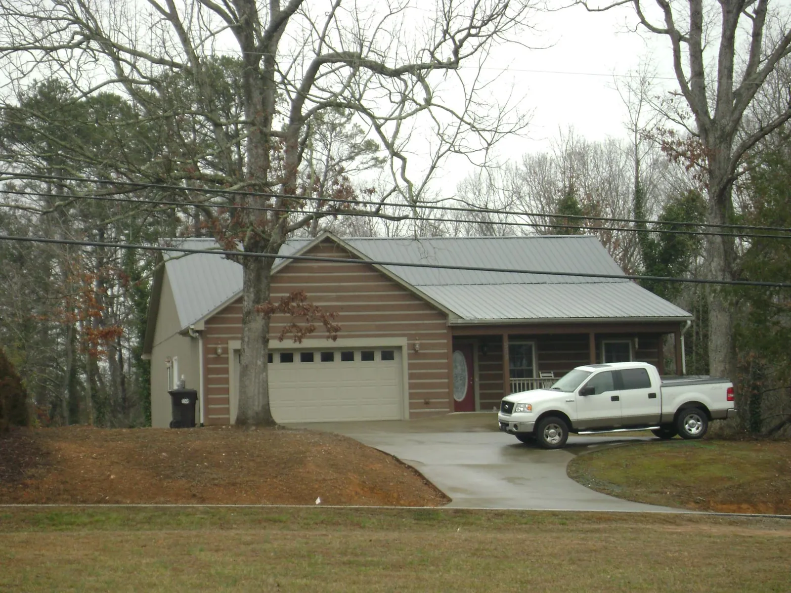 Gray metal roof on a log sided house with an attached two car garage in East Sparta