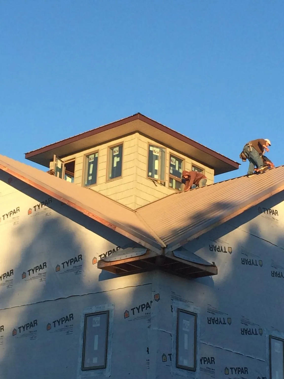Roofers working around a rooftop cupola on a new metal roof at sunset — Roof Waterproofing in East Sparta by Roofing Brothers